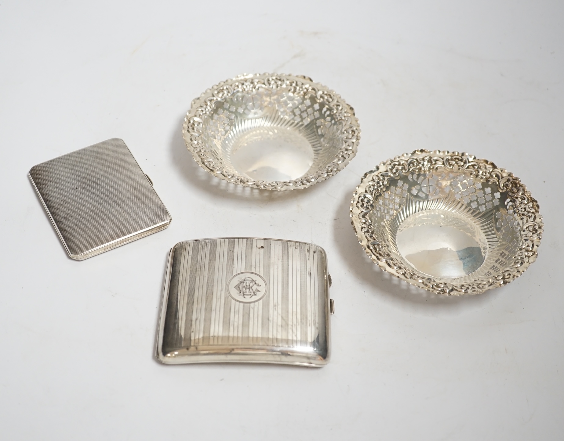 A pair of late Victorian pierced silver bonbon dishes, Birmingham, 1896, diameter 11.1cm, together with two silver cigarette cases.